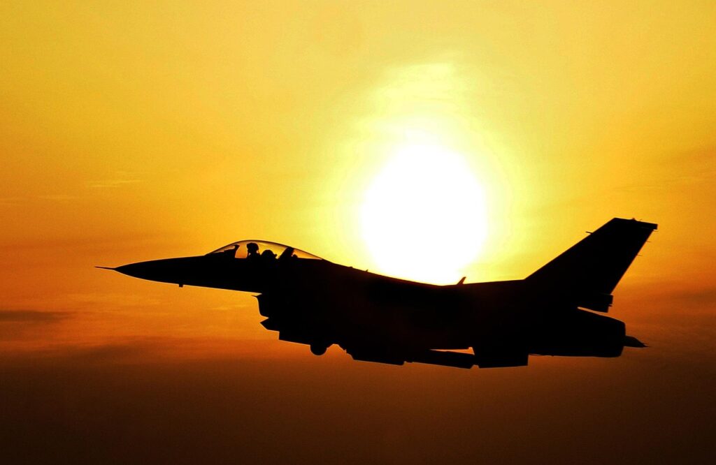 夕暮れの空を飛ぶ戦闘機のシルエット